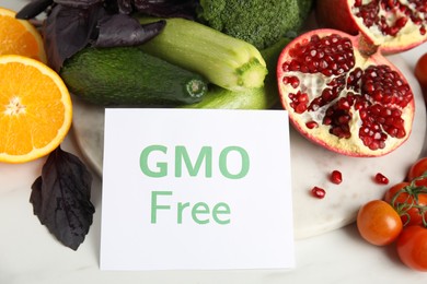 Photo of Tasty fresh GMO free products and paper card on white table, above view