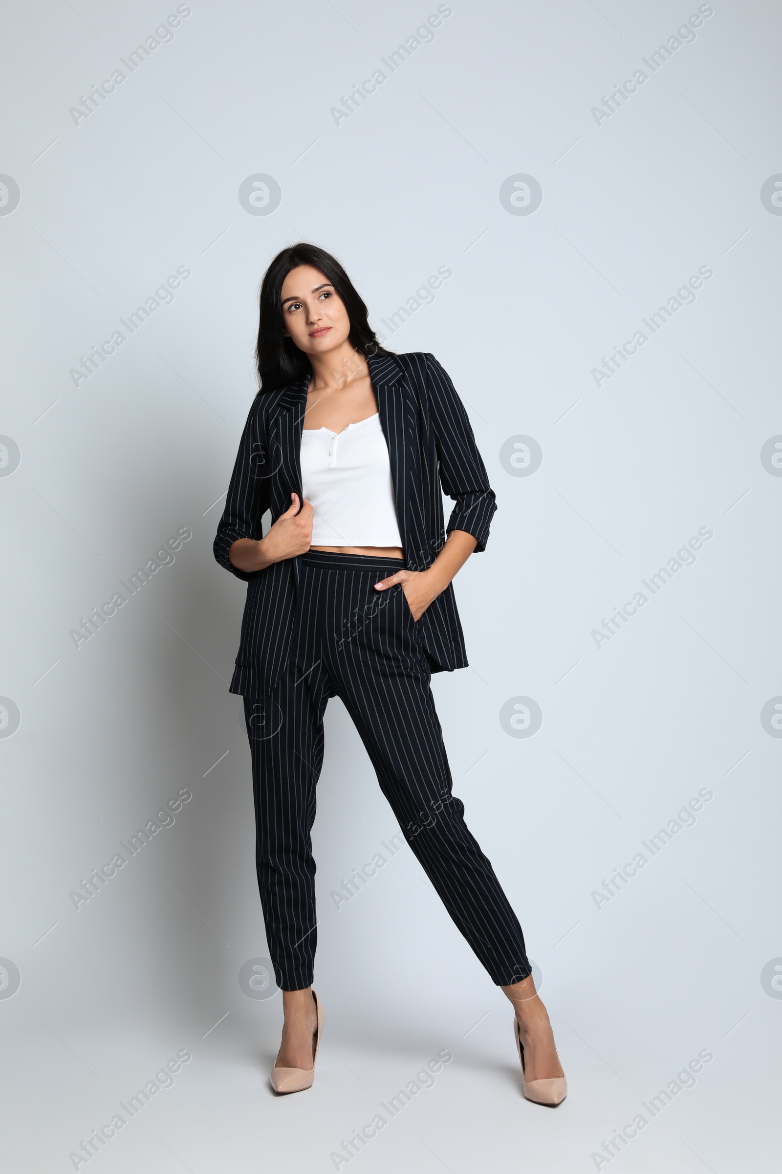 Photo of Full length portrait of beautiful woman in formal suit on light background. Business attire