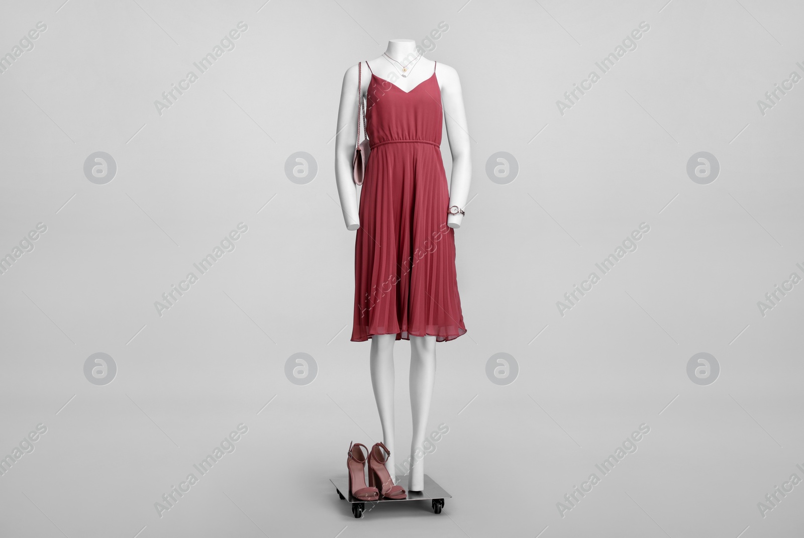 Photo of Female mannequin with necklace and bag dressed in stylish red dress on grey background