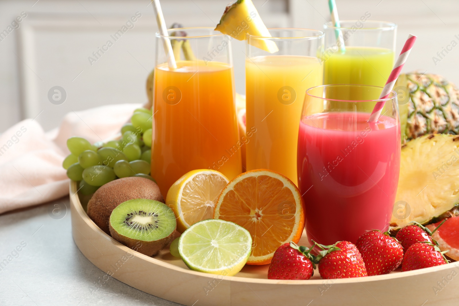 Photo of Wooden tray with glasses of different juices and fresh fruits on table