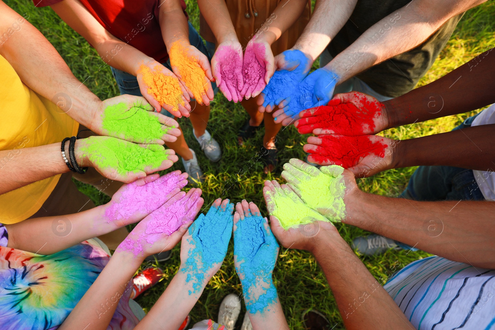 Photo of Friends with colorful powder dyes outdoors, closeup. Holi festival celebration