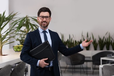 Happy real estate agent with leather portfolio in office