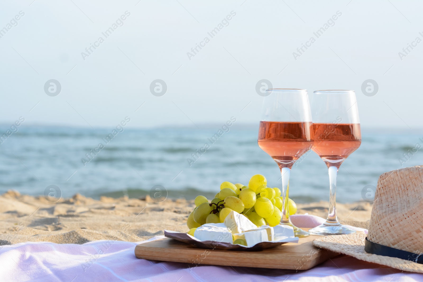 Photo of Glasses with rose wine and snacks on sandy seashore. Space for text