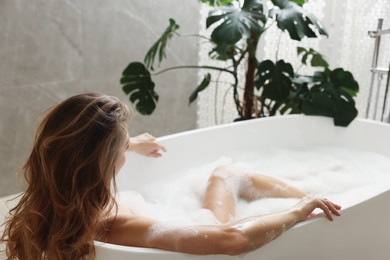 Photo of Beautiful woman taking bath with foam indoors