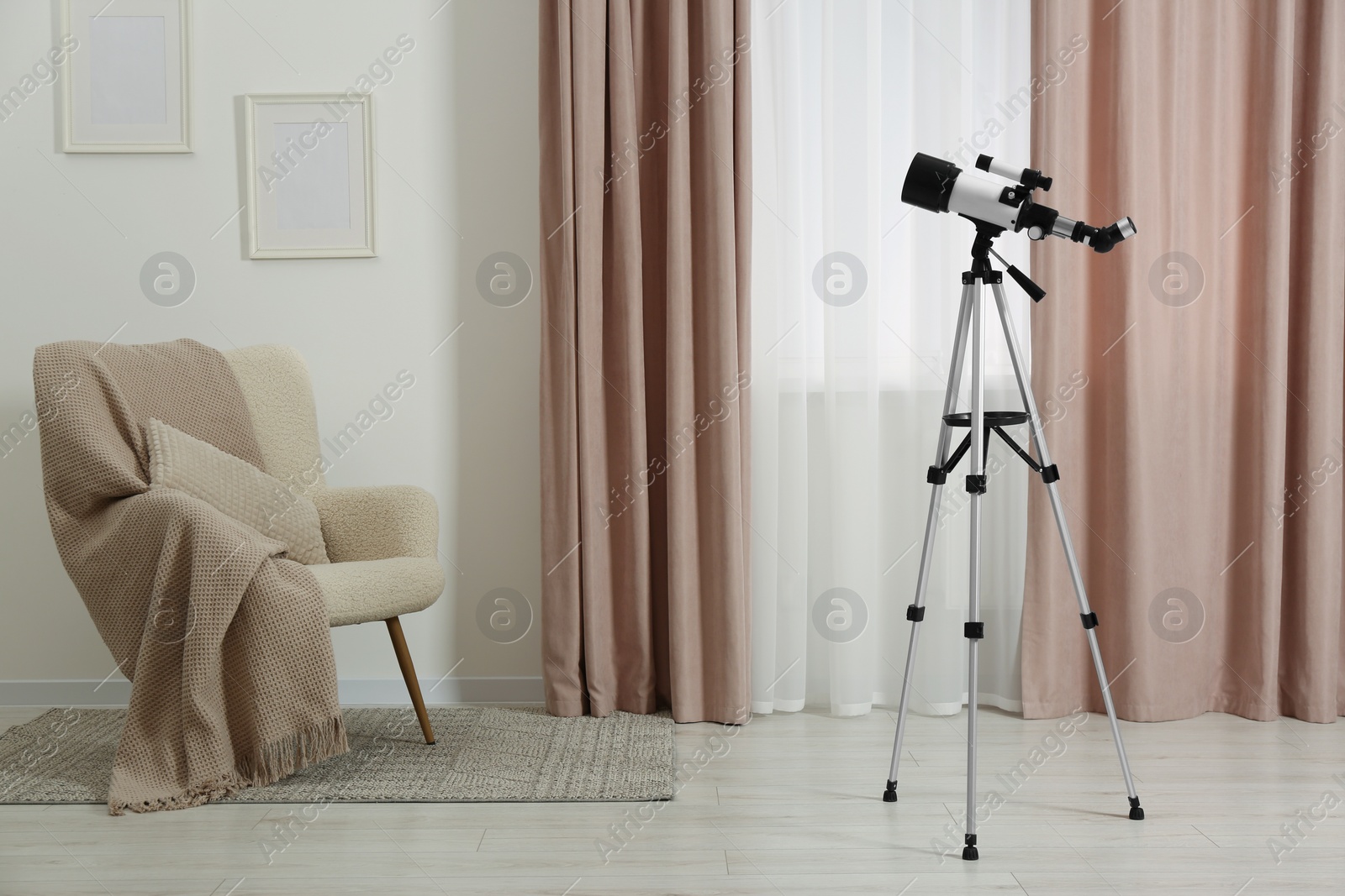 Photo of Tripod with modern telescope in stylish room