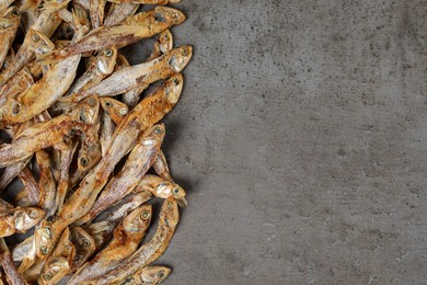 Photo of Tasty dried anchovies on grey table, flat lay. Space for text