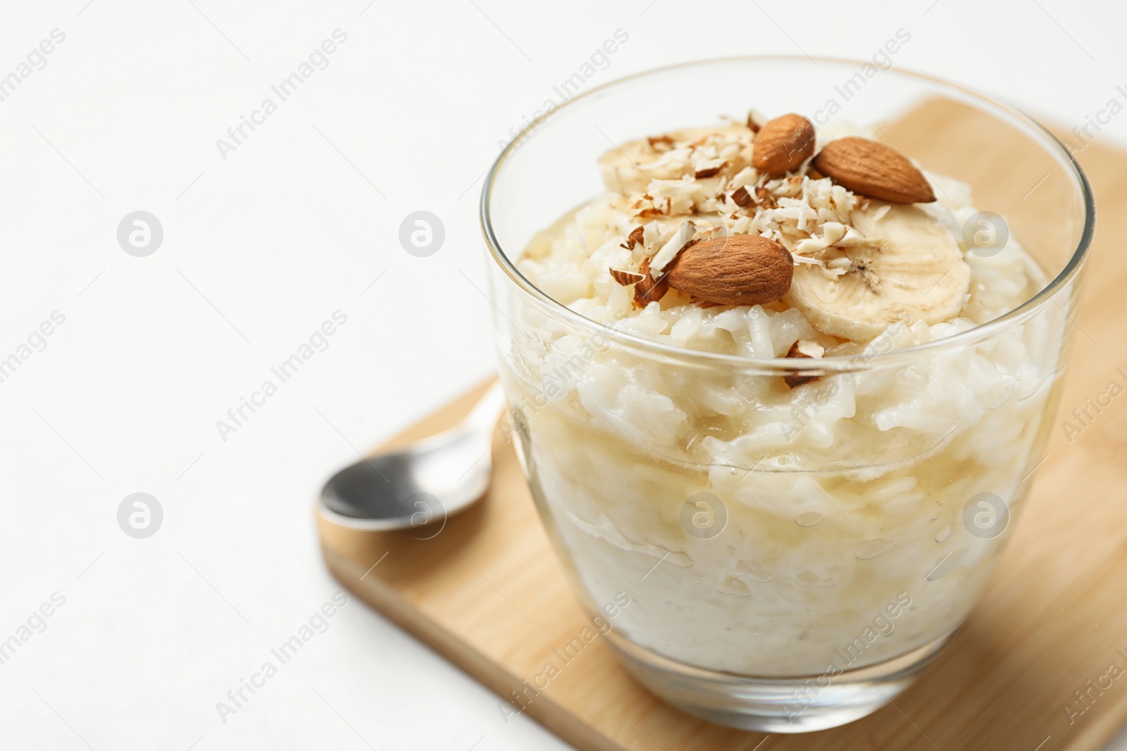Photo of Delicious rice pudding with banana and almonds on white table, closeup