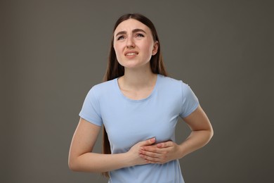 Woman having heart attack on grey background