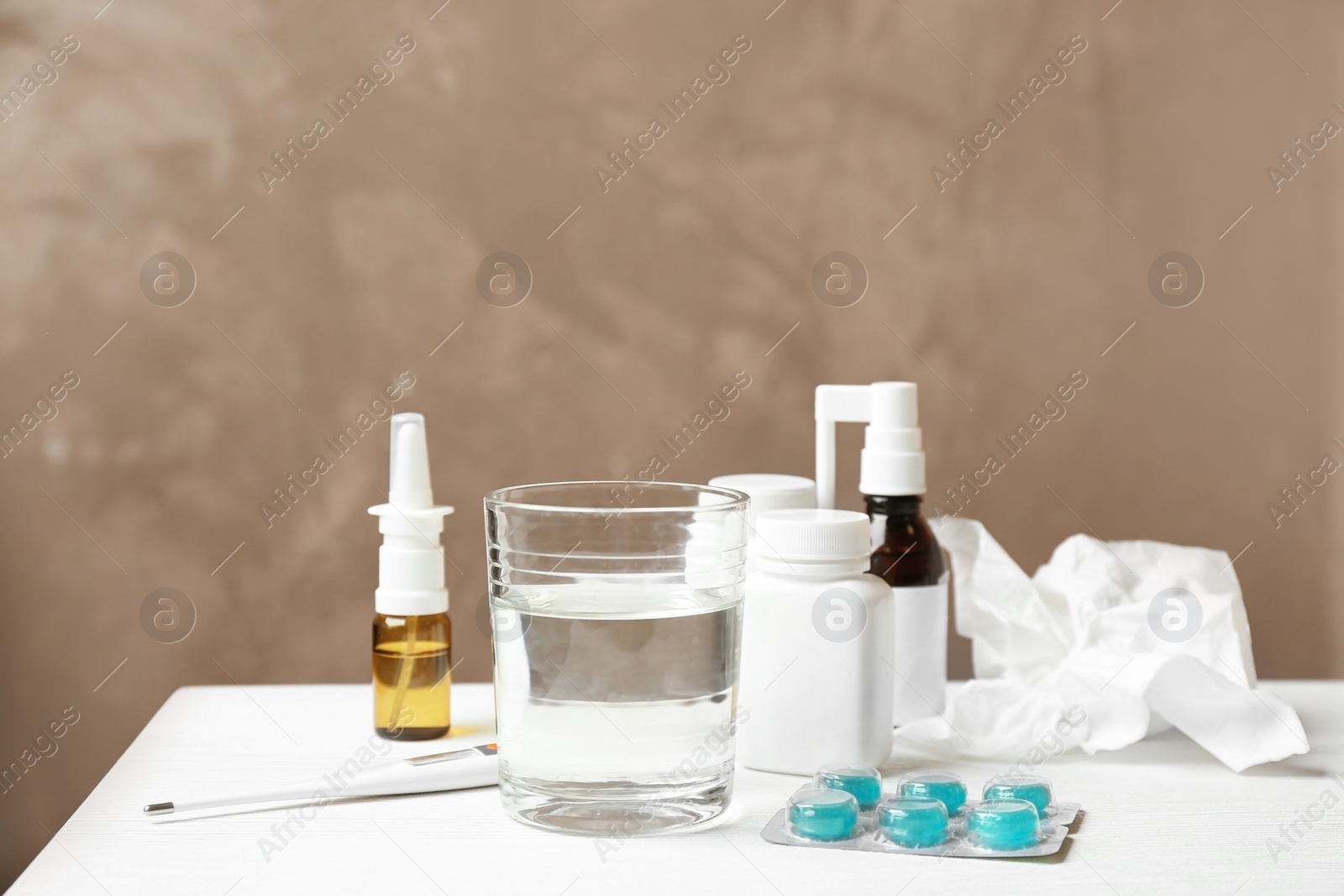 Photo of Glass of water, pills and drugs for cold on table