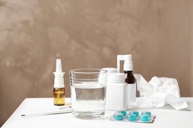 Photo of Glass of water, pills and drugs for cold on table