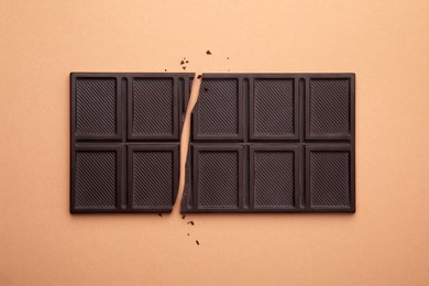 Photo of Broken chocolate bar on brown background, top view