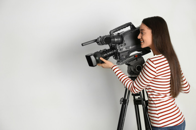 Operator with professional video camera on white background, space for text