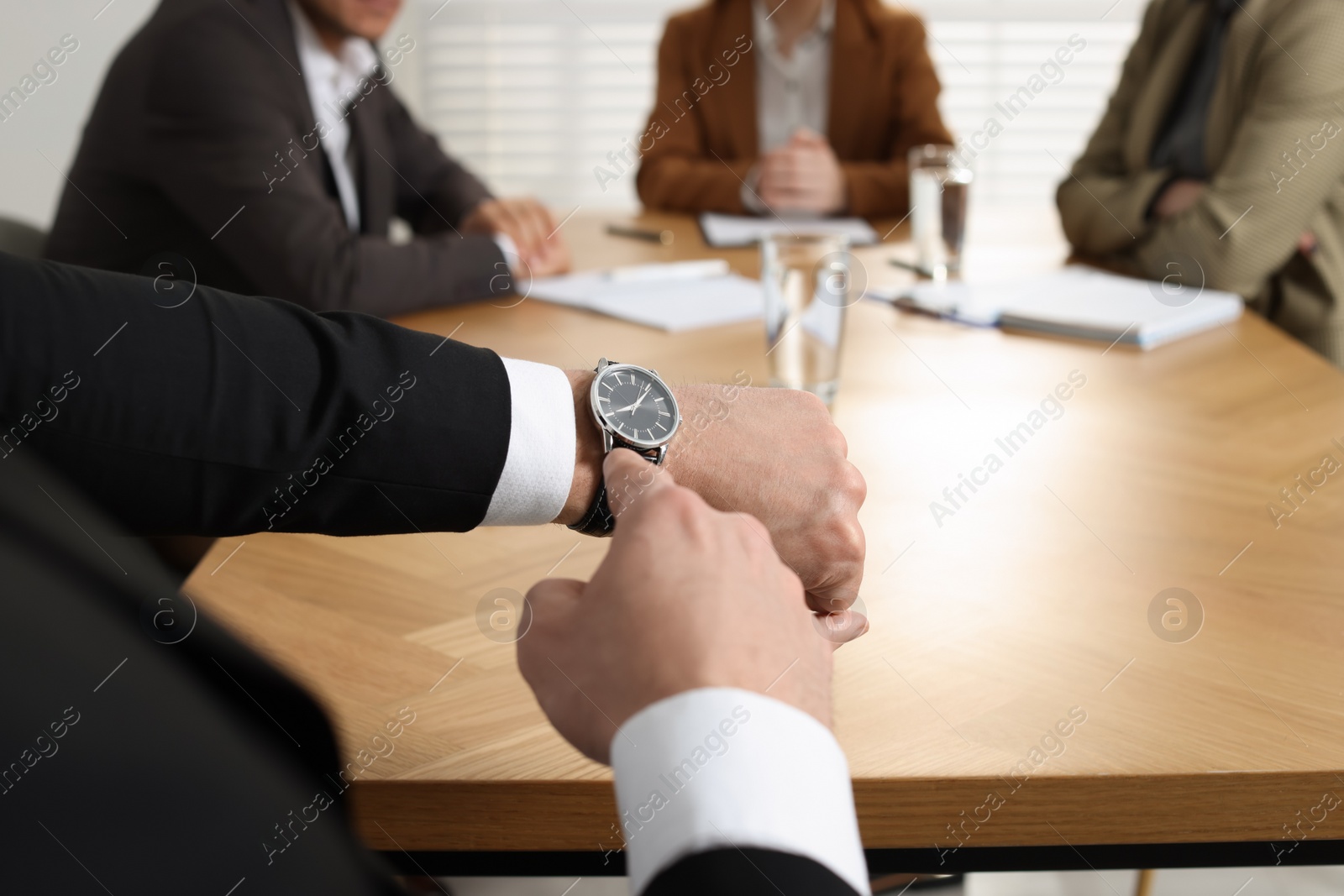 Photo of Businessman pointing on wrist watch while scolding employee for being late in office, closeup