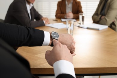 Photo of Businessman pointing on wrist watch while scolding employee for being late in office, closeup