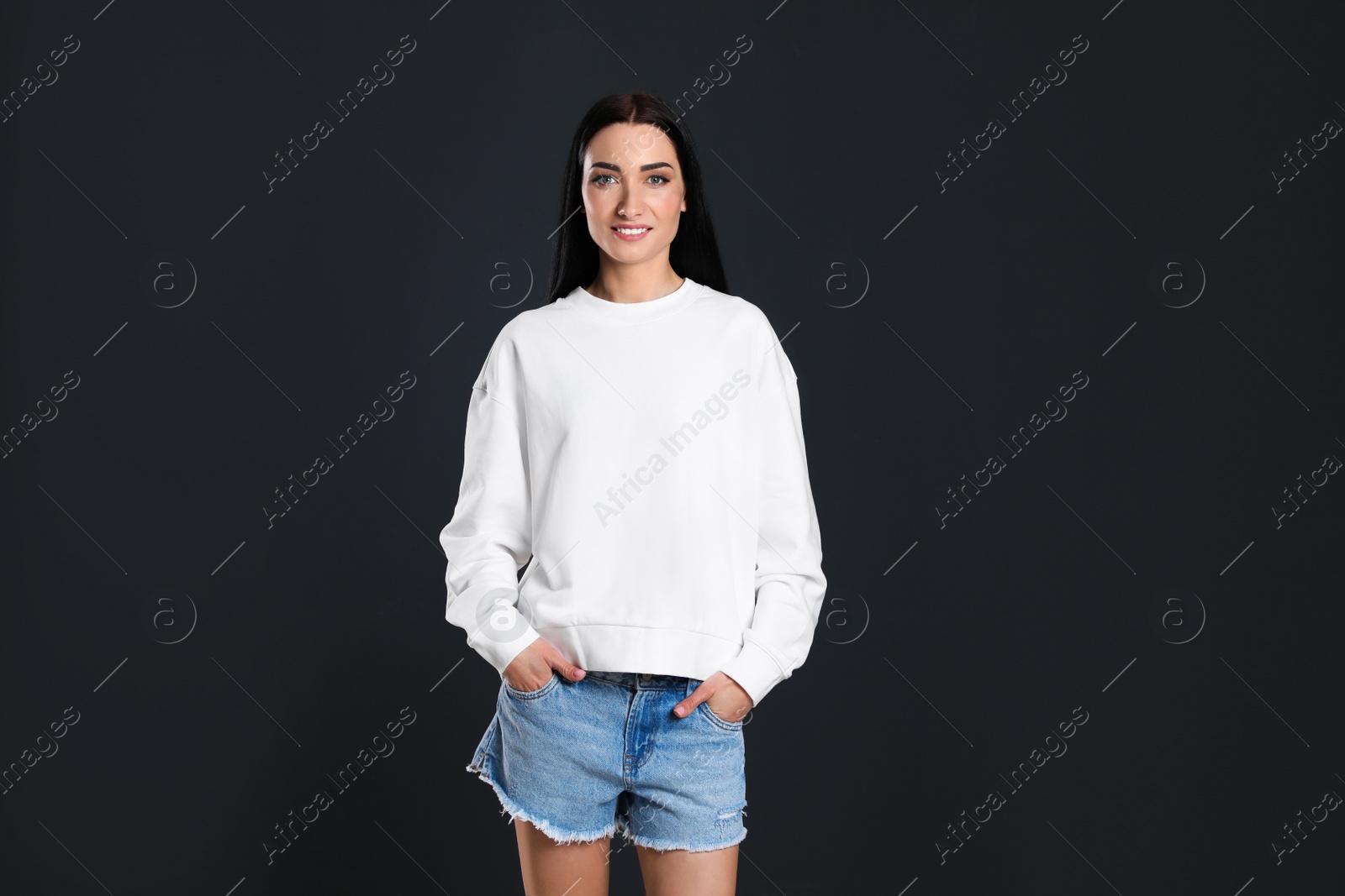 Photo of Portrait of young woman in sweater on black background. Mock up for design