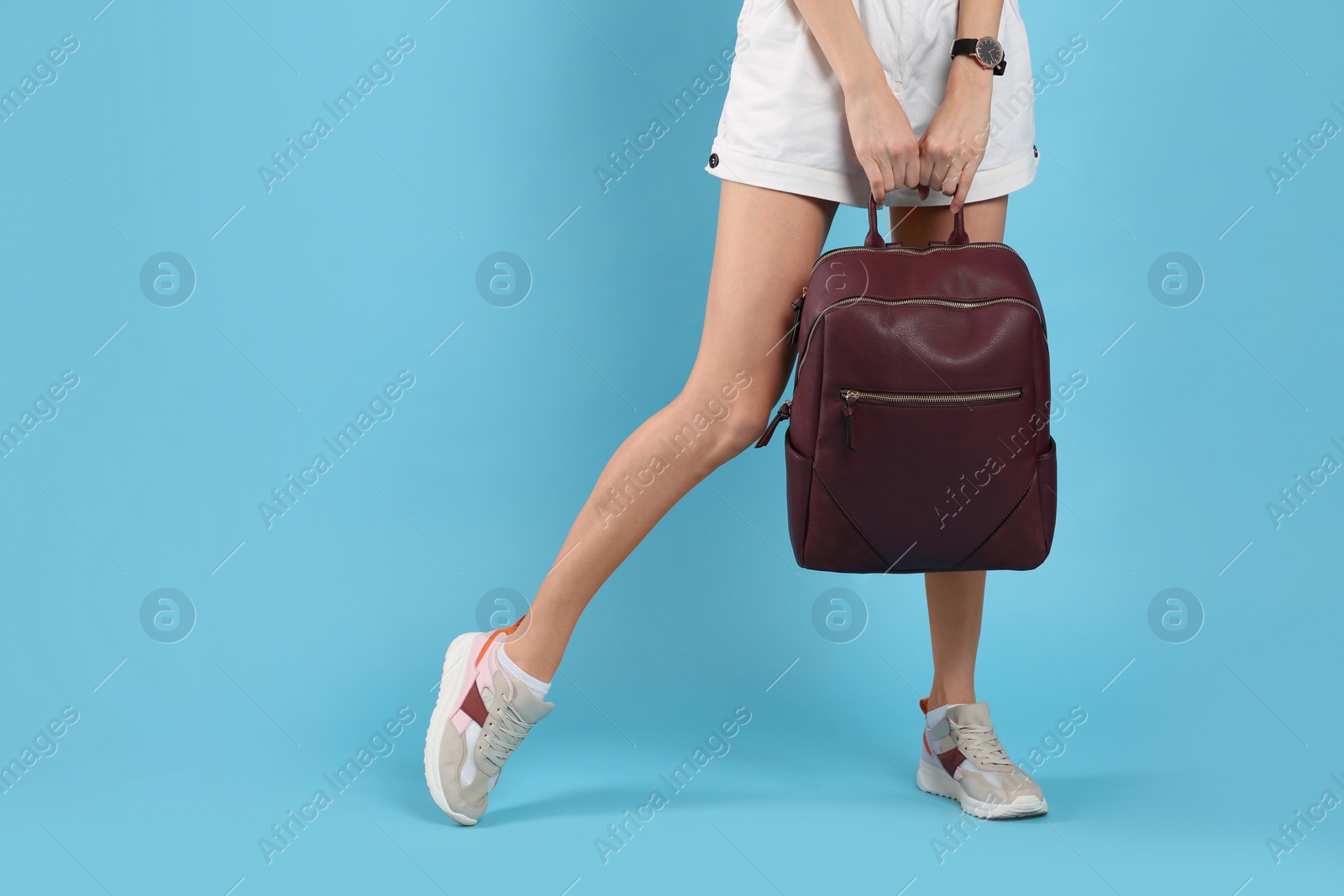 Photo of Woman with backpack on light blue background, closeup. Space for text