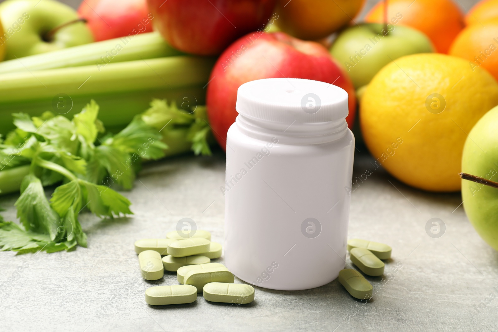 Photo of Dietary supplements. Blank white bottle and pills near food products on grey textured table, closeup. Space for text