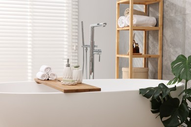 Photo of Different personal care products on bath tub in bathroom