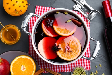 Delicious mulled wine and ingredients on grey table, flat lay