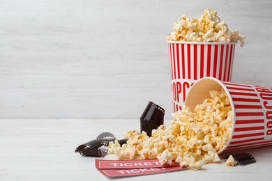 Photo of Popcorn, tickets and film footage on white wooden table, space for text. Cinema snack
