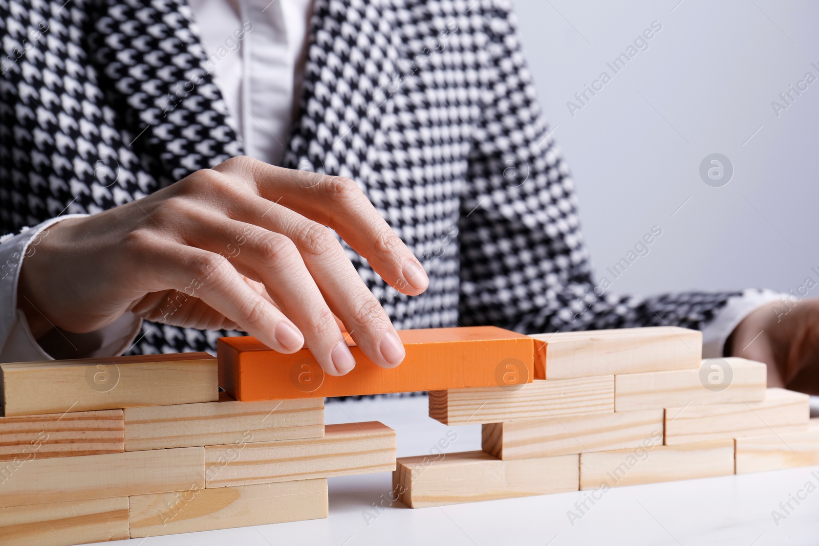 Photo of Businesswoman building bridge with wooden blocks at table, closeup. Connection, relationships and deal concept