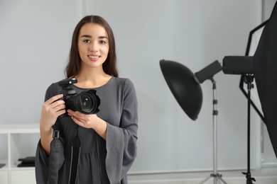 Photo of Young woman with professional camera in photo studio. Space for text