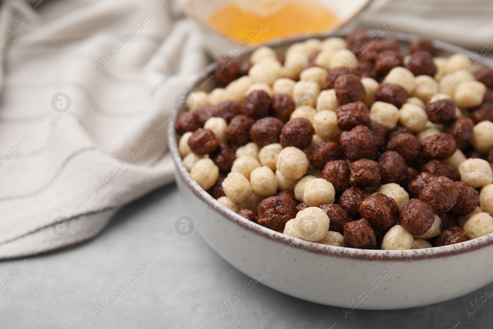 Photo of Tasty cereal balls in bowl on grey table, closeup. Space for text