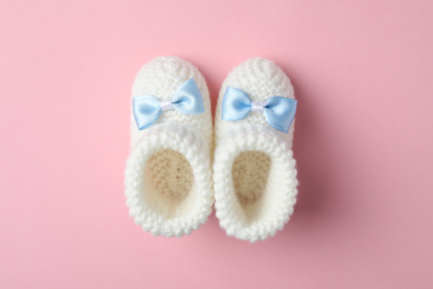 Photo of Handmade child's booties on pink background, flat lay