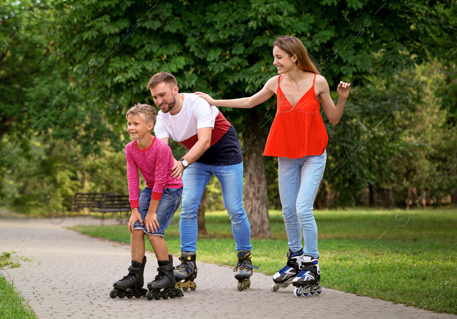 Photo of Young happy family roller skating in summer park