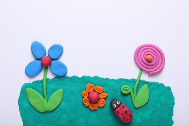 Flowers and ladybug made of plasticine on white background, top view