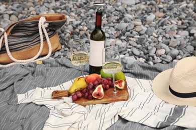 Photo of White wine and fresh fruits on picnic blanket outdoors