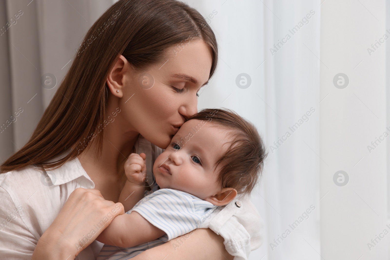 Photo of Happy mother kissing her little baby at home