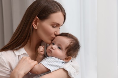 Happy mother kissing her little baby at home