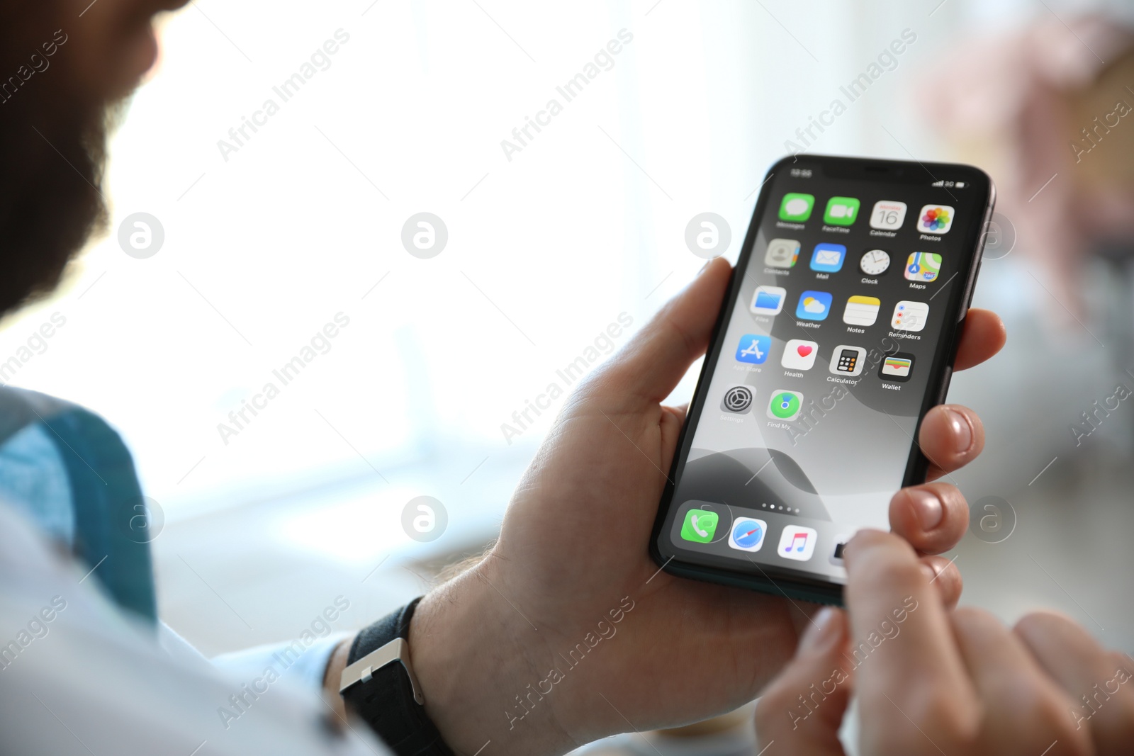 Photo of MYKOLAIV, UKRAINE - MARCH 16, 2020: Man holding iPhone 11 with home screen indoors, closeup