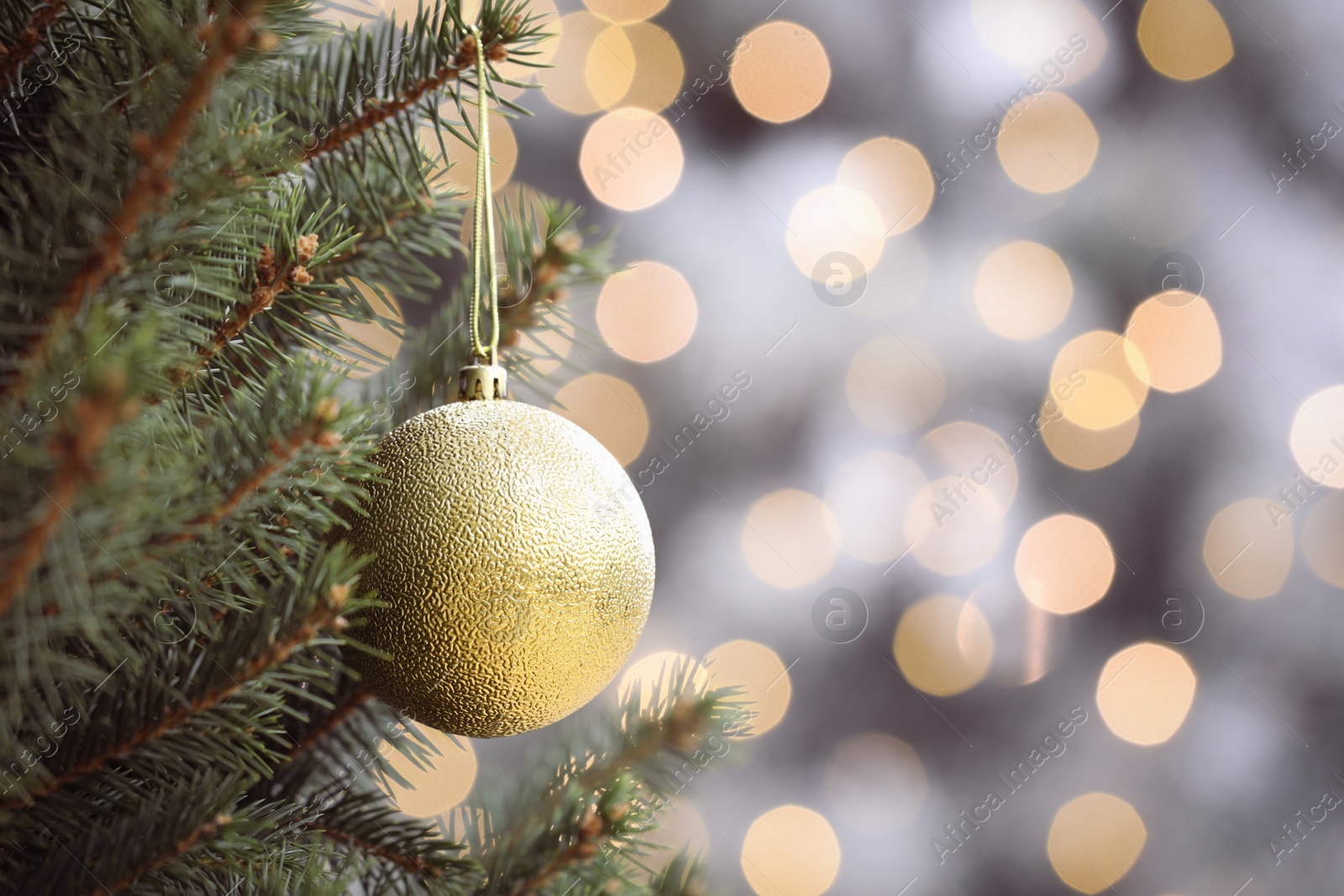 Photo of Shiny green ball hanging on Christmas tree against festive lights. Space for text