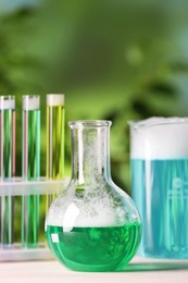 Laboratory glassware and test tubes with colorful liquids on white table. Chemical reaction