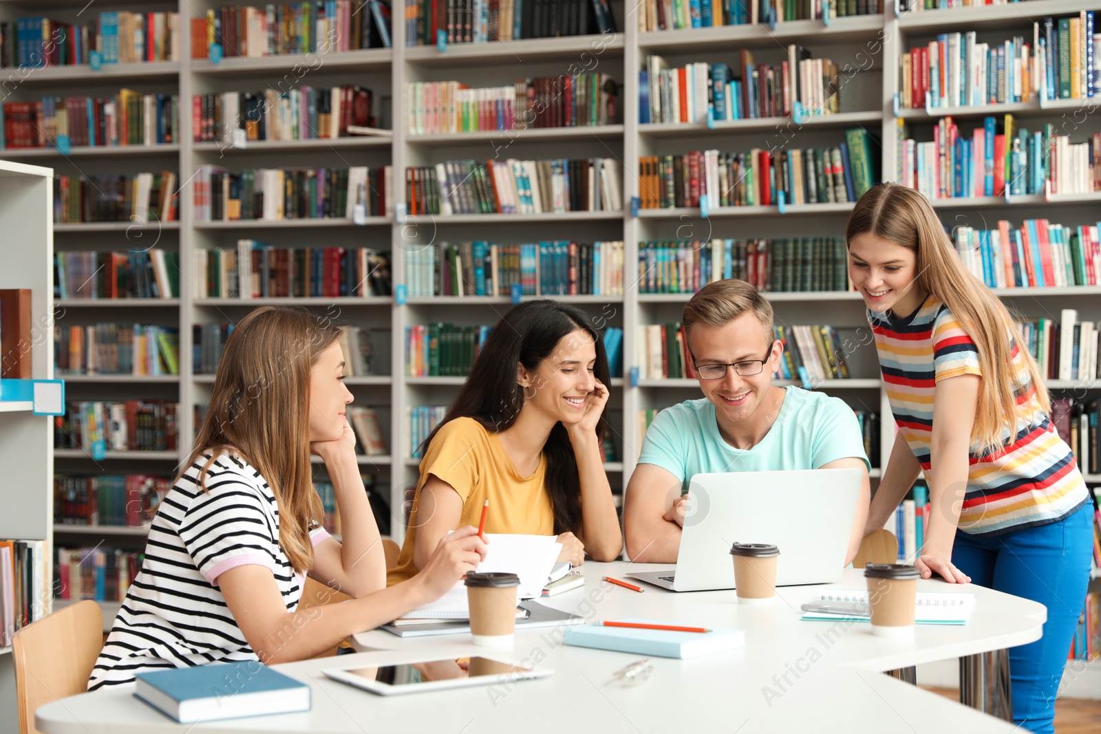 Photo of Young people discussing group project at table in library