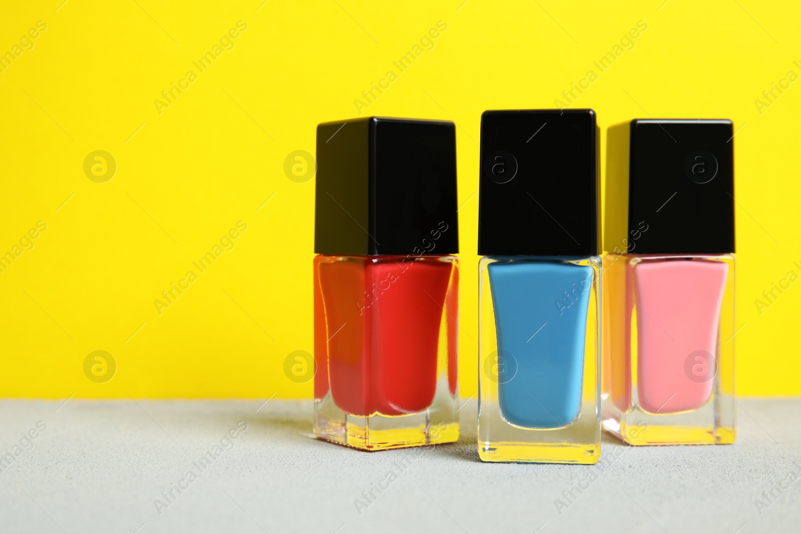 Photo of Bright nail polishes on table against color background. Space for text