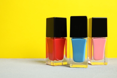 Bright nail polishes on table against color background. Space for text