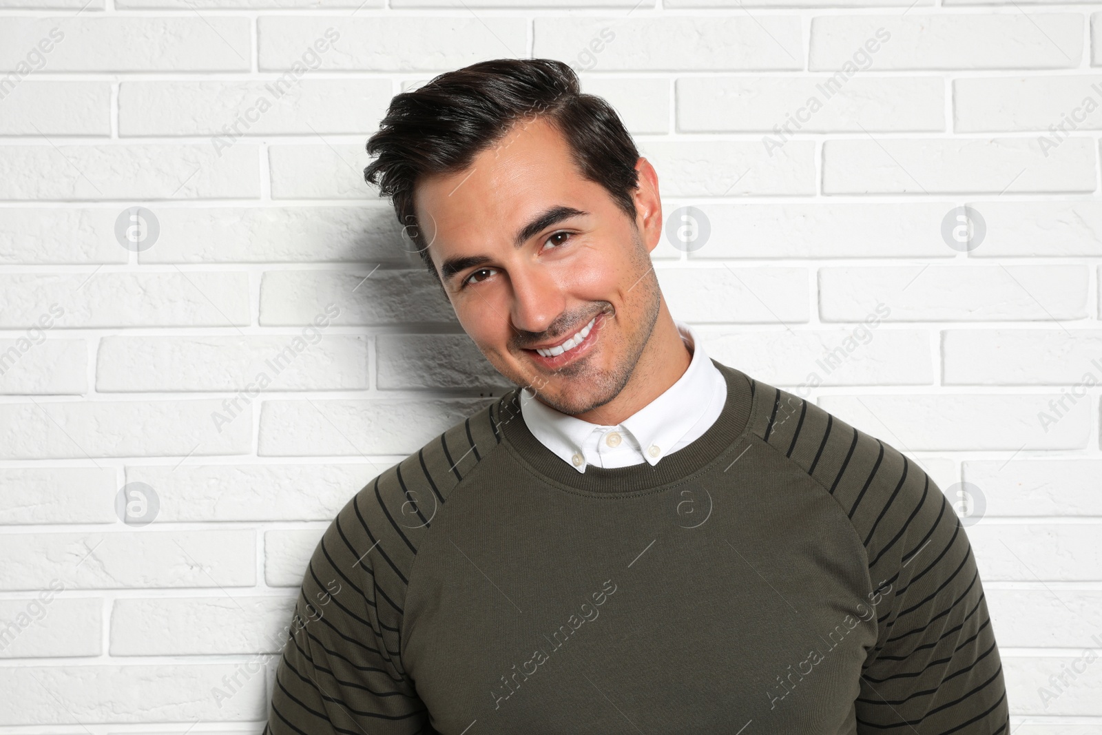 Photo of Portrait of handsome young man on white brick wall