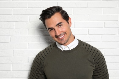 Photo of Portrait of handsome young man on white brick wall