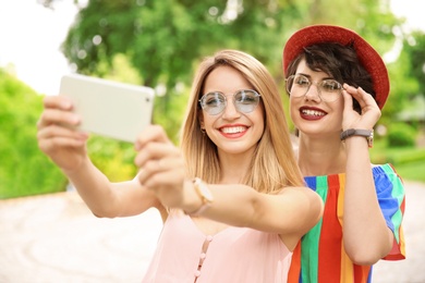 Young women in stylish clothes taking selfie outdoors