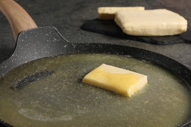 Photo of Melting butter in frying pan on grey table, closeup