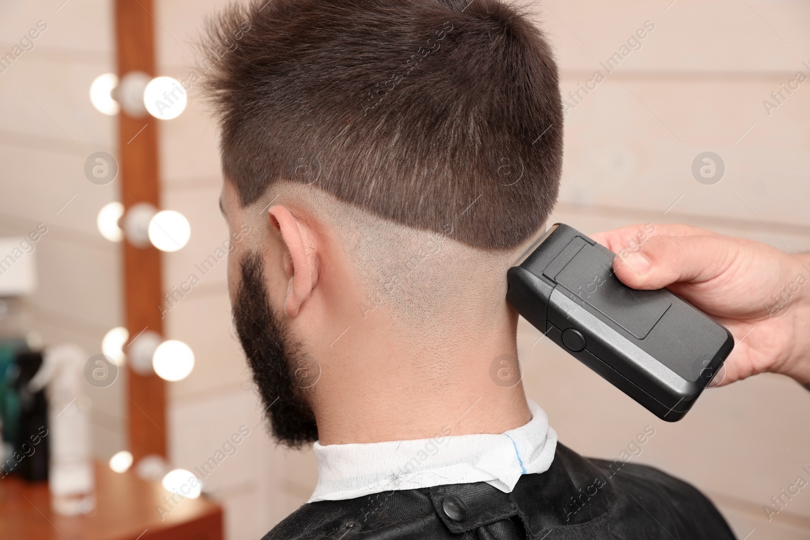 Photo of Professional hairdresser working with client in barbershop, closeup