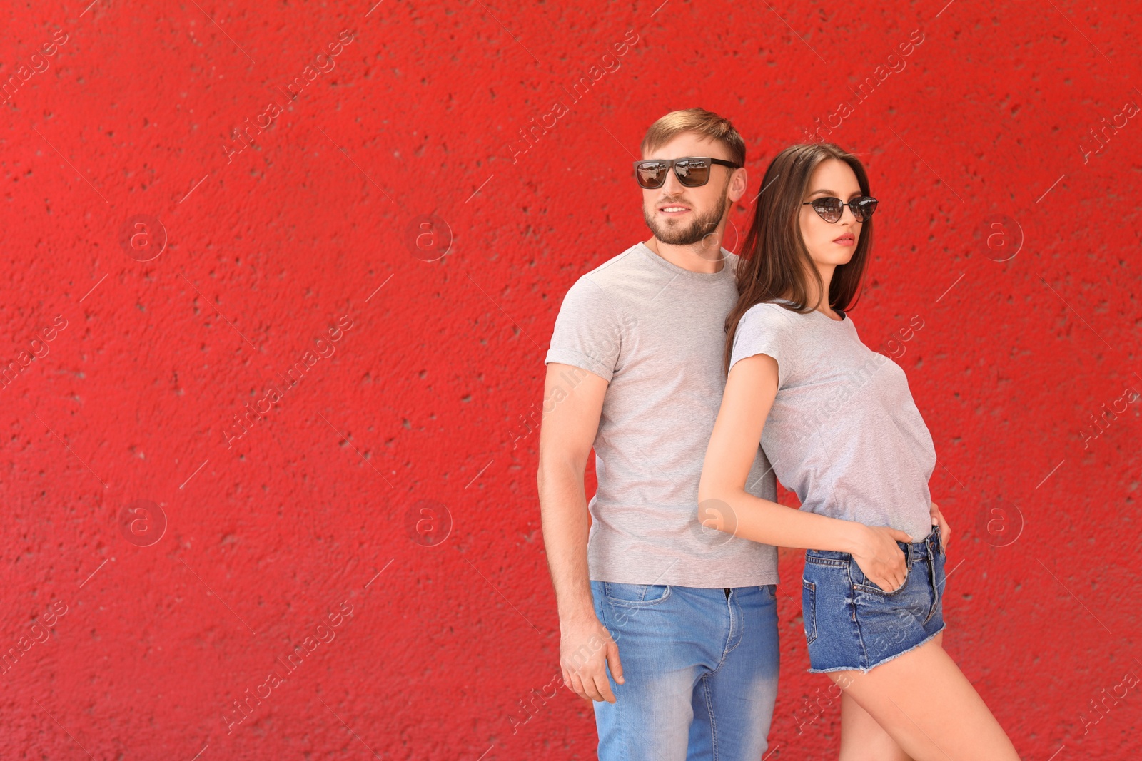 Photo of Young couple wearing gray t-shirts near color wall on street