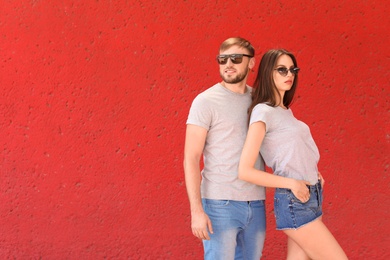 Young couple wearing gray t-shirts near color wall on street