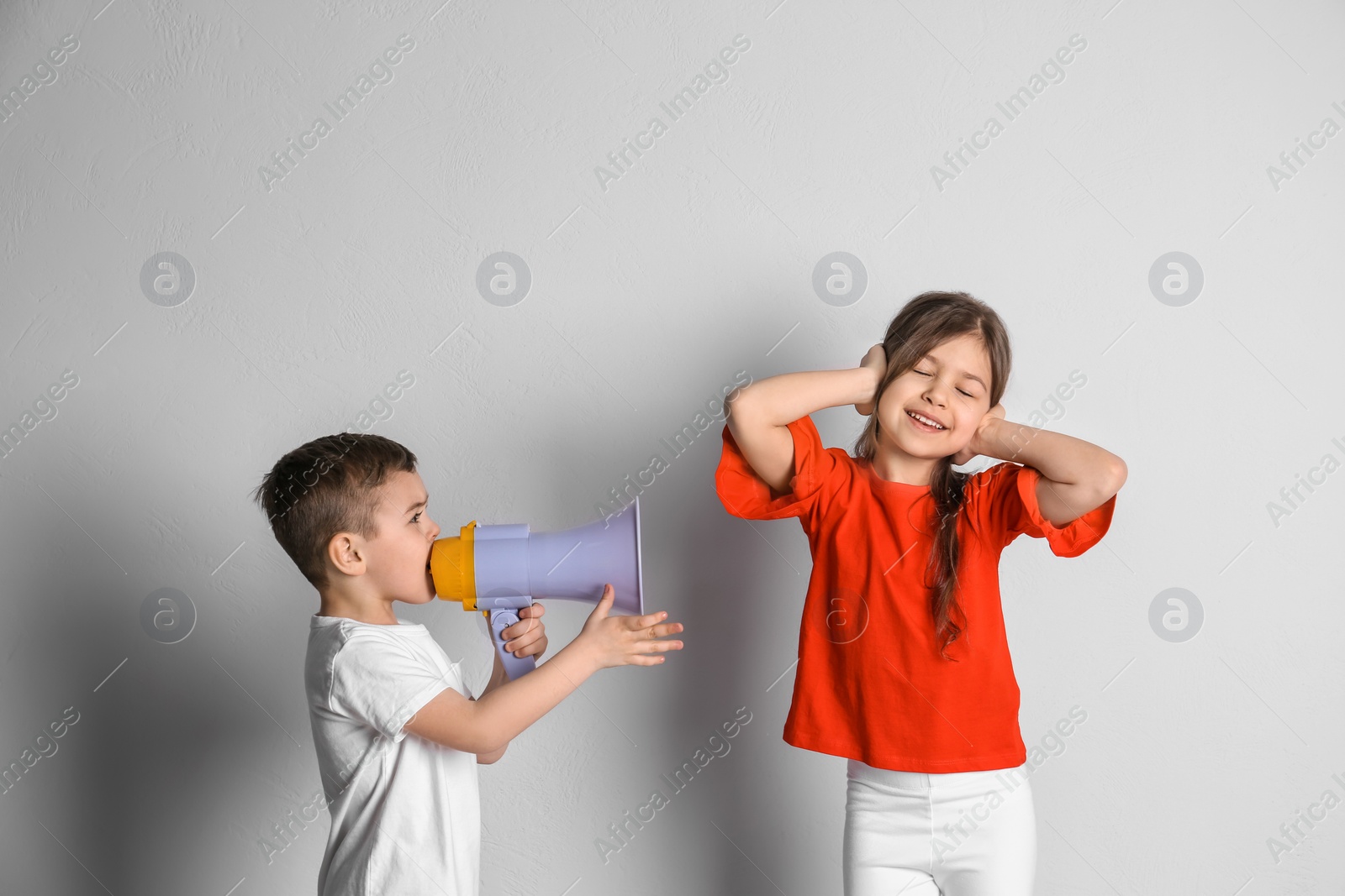 Photo of Adorable little kids with megaphone on light background