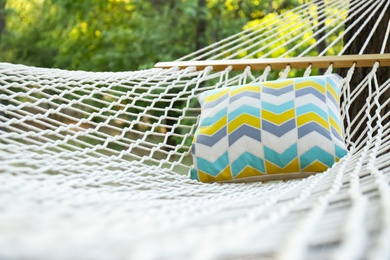 Comfortable net hammock with soft pillow at green garden, closeup