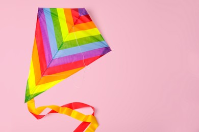 Photo of Bright rainbow kite on pink background, top view. Space for text