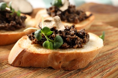 Photo of Delicious bruschetta with truffle sauce and microgreens on wooden table, closeup